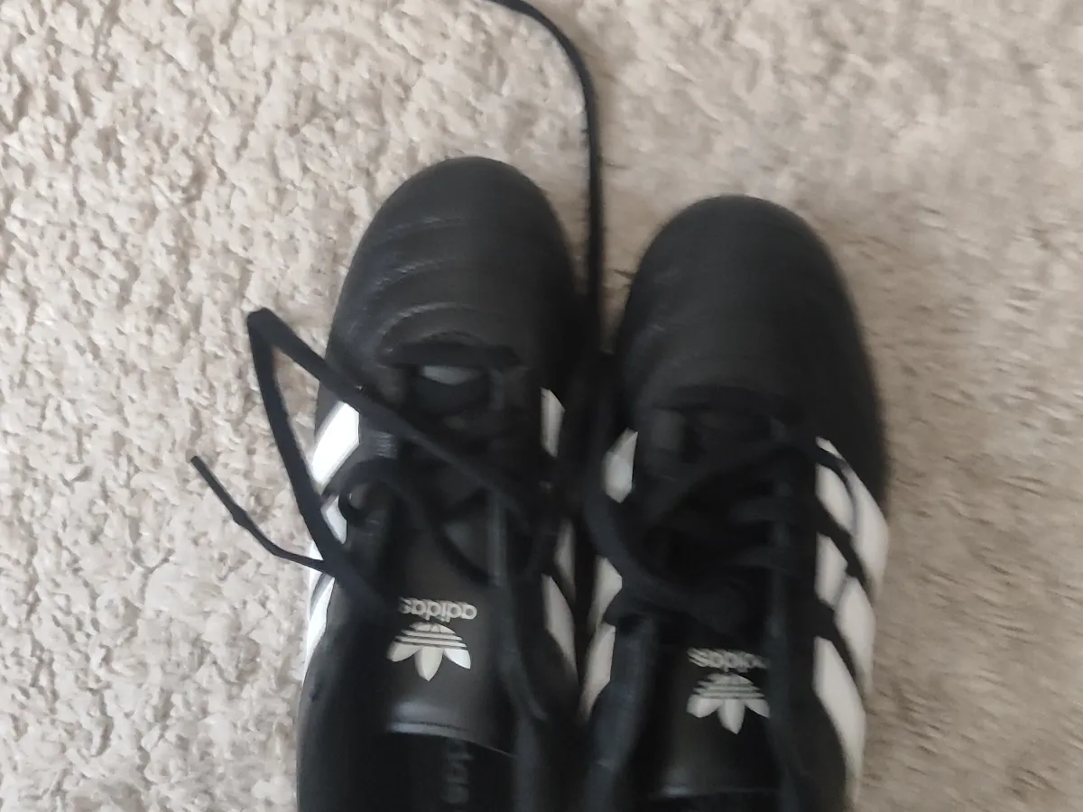 A pair of black football boots with white stripes